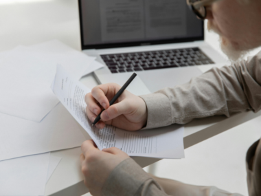 Professional filling out a business visa application form with passport and documents on a desk.