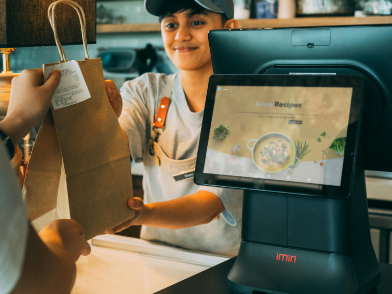 A supermarket cashier efficiently bagging grocery items for a customer at the checkout counter.